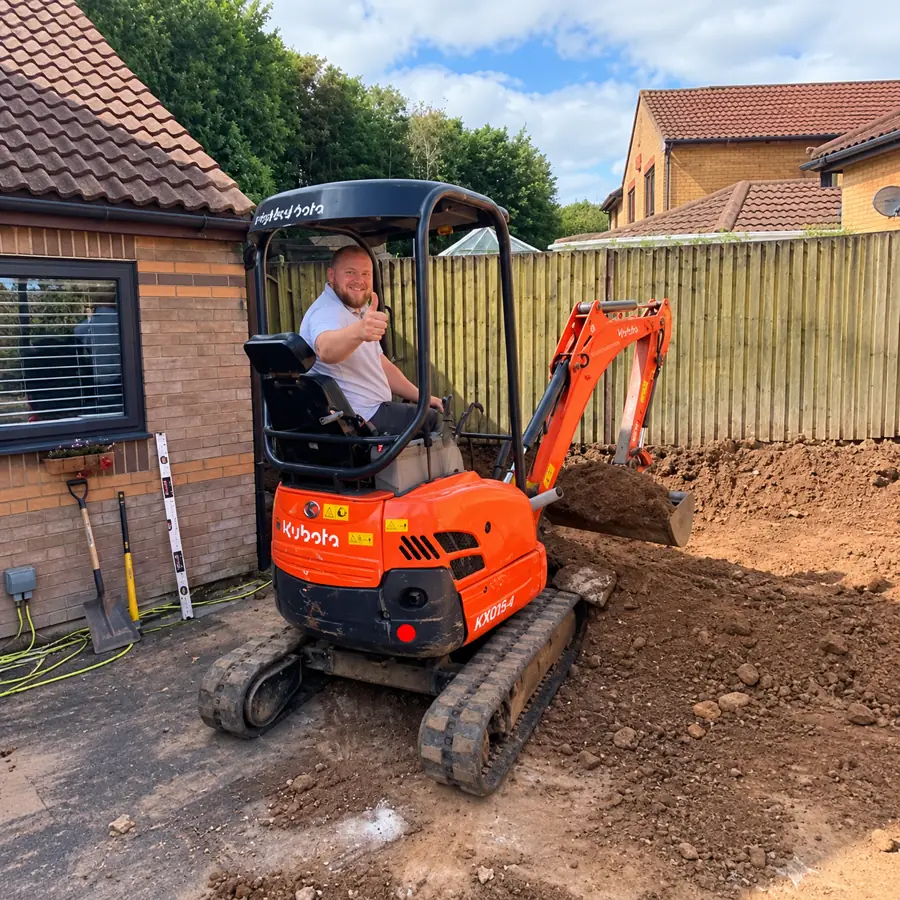Tom, owner of TP Home Improvements, operating a mini digger on a landscaping project