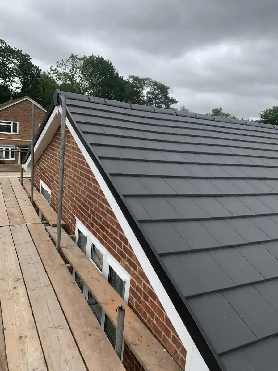 Newly installed dark grey flat interlocking tile roof with dry ridge